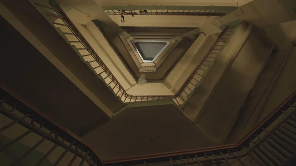 Des escaliers. Images d'archives. Vue du bas des volées vertigineuses d'escaliers. Escaliers torsadés dans un immeuble de plusieurs étages. Le paquet tombe du dernier étage sur les escaliers — Photo