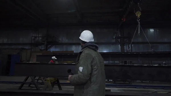 Mannen går runt fabriken och ser sig omkring. Klipp. Foreman övervakar arbete och produktion av alla delar av anläggningen. Ingenjör eller förman övervakar produktionen på fabriken — Stockfoto