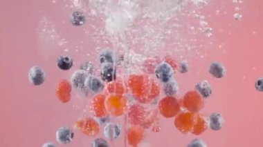 Çilekler izole arka planda suya düşer. Başla. Meyveler kabarcıklarla suya düşer. Hafif arkaplandaki dutların ferahlatıcı düşüşü