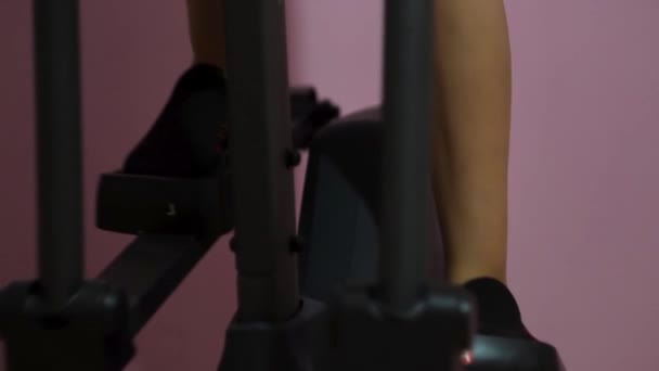 Gros plan des jambes minces d'une fille qui s'entraîne sur une ellipse au gymnase. Concept. Appareil de fitness et sport pour la santé féminine et les soins du corps. — Video