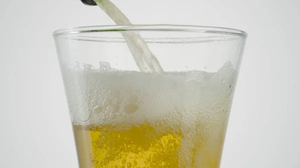 Крупним планом пиво розливають у прозоре скло. Дія. Пиво наливають у прозоре скло на білому ізольованому фоні. Пиво наливають у склянку — стокове фото