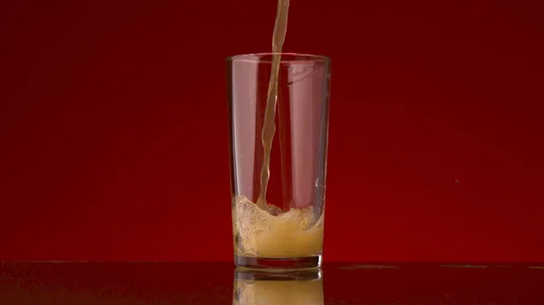 Наливання апельсинового соку в склянку ізольовано на червоному тлі. Стокові кадри. Концепція здорового харчування, вітаміну С та імунітету . — стокове фото