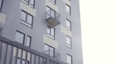 Yeni bir apartmanın ve siyah demir çitin dışı. Başla. Pencereleri ve balkonları olan çok katlı bir evin alt görüntüsü.