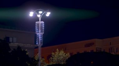 Parlak çelenklerle süslenmiş güzel fenerlerle dolu bir gece sokağı manzarası. Stok görüntüleri. Gece yarısı parlayan sokak lambalarıyla şehir manzarası.