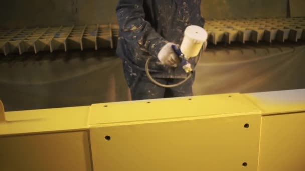 男は塗料スプレーで黄色で大きな金属の詳細を塗装します。クリップ。工場での絵画、金属構造物のエアロゾル塗装. — ストック動画
