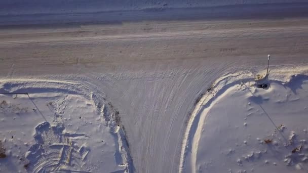 Křižovatka ve tvaru T za zimního slunečného dne. Akce. Letecký pohled shora na krajinu silničního úseku pokrytého sněhem. — Stock video