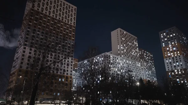 Hermosos edificios residenciales en el fondo del cielo nocturno. Acción. Vista inferior de edificios de varios pisos con ventanas brillantes en la noche —  Fotos de Stock