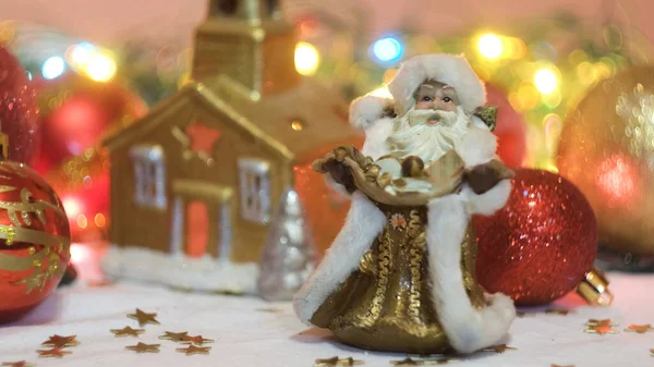 Noel ve yeni yıl süslemeleri, çocuk oyuncakları Peder Frost ve altın bir ev. Kavram. Yanıp sönen çelenk ve güzel kompozisyon oyuncaklar, konfeti, beyaz karlı kumaş ve parlayan — Stok fotoğraf