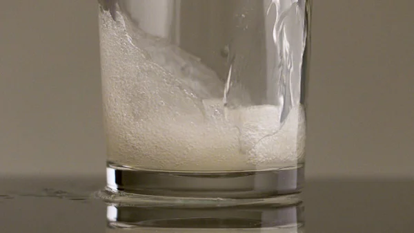 Enchimento de vidro com água com gás em câmera lenta. Imagens de stock. Close-up de verter refrigerante com muitas bolhas dentro do vidro transparente. — Fotografia de Stock