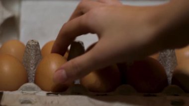 Mutfak masasında taze organik yumurtaların olduğu karton kutuyu kapat. Kavram. Baker kadın eli yemek pişirmek için konteynırdan iki yumurta alıyor..