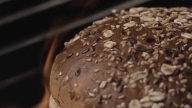 Fırında pişirilmiş ev yapımı yuvarlak ekmek somununu yakın ateşte pişirin. Stok görüntüleri. Tohumlu kahverengi ekmek ve siyah arka planda mısır gevreği..