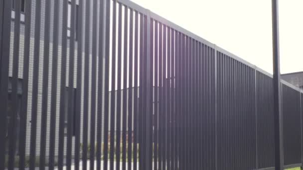 Apartment buildings with metal fence railing. Action. Close up of black iron fence with an apartment house and sky on the background. — Stock Video