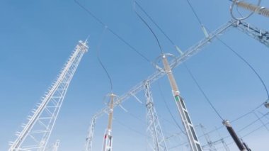 Elektrik kabloları olan dijital bir alt istasyon. Başla. Mavi gökyüzünün arka planında kablolar ve trafolar olan elektrik direklerinin alt görüntüsü. Açık mavi gökyüzünün arka planında elektrik santrali kutupları