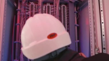 Elektrik kablolara bakıyor. Başla. Girişimdeki birçok kabloyu panele bağlayan adama yakın çekim. Profesyonel elektrikçi şirkette bir sürü kabloyla uğraşır.