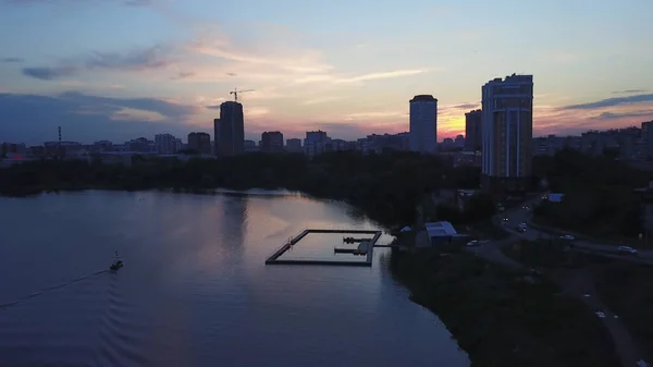 在阴沉沉的落日的天空下,空中俯瞰着河流和城市的风景.库存录像。城镇的不同建筑、自然与城市化的概念. — 图库照片