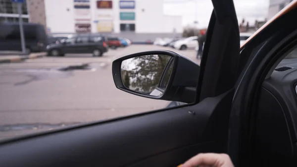 Vue de l'intérieur d'une voiture, d'un miroir latéral et d'une main de femme essayant d'ouvrir la porte. L'action. Détails intérieurs de la voiture et un 4x4 passant derrière la fenêtre. — Photo