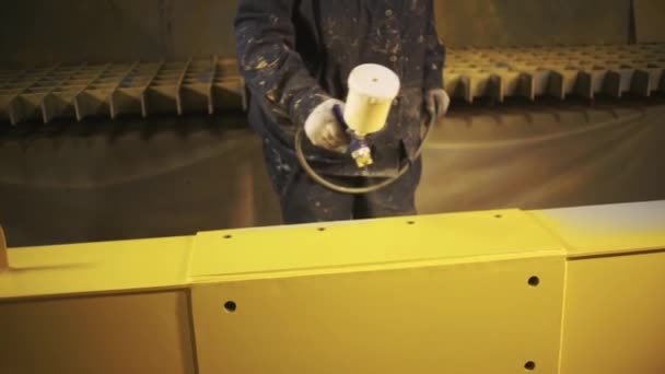 Mann bemalt ein großes Metalldetail in gelb mit Farbspray. Clip. Malerei in der Fabrik, Aerosollackierung von Metallkonstruktionen. — Stockvideo