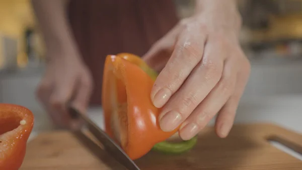Primo piano di donna che taglia il dolce pepe. Azione. Donna sceglie coltello per affettare le verdure. Donna taglia dolce pepe con coltello appositamente affilato — Foto Stock
