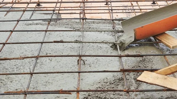 Pouring concrete mixture to the reinforcing mesh and a house foundation. Clip. Pouring liquid cement at a construction site.