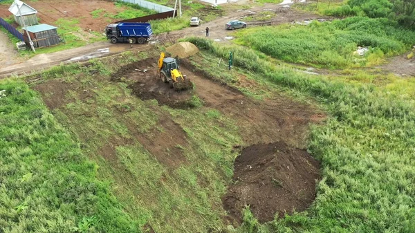 Widok z lotu ptaka na początek budowy nowego domu. Klip. Ciągnik robi dziurę pod fundamentem domu na wsi.. — Zdjęcie stockowe