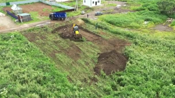 Yeni ev inşaatının havadan görünüşü. Şarjör. Traktör kırsal bölgedeki ev temeli için bir delik açıyor.. — Stok video