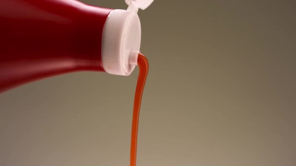 Adăugarea de sos de roșii dintr-o sticlă de plastic de culoare roșie. Înregistrări stoc. Turnarea ketchup natural izolat pe fundal de perete bej . — Videoclip de stoc