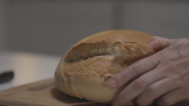 Beyaz ekmeği yavaş çekimde dilimleyen kadın ellerini ahşap bir tahtada kapat. Başla. Çelik bir bıçakla taze pişmiş, yuvarlak, beyaz ekmek dilimliyorum..