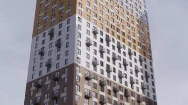 Mavi gökyüzüyle çevrili yüksek katlı bir apartman. Başla. Gri ve turuncu renkli yeni yapılmış çok katlı bir ev.. 