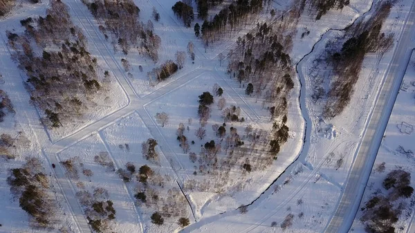 Drone vista aérea de pueblo rural tradicional situado en un lugar tranquilo con aire fresco y bosque. Acción. Paisaje invernal con pequeñas casas en nieve, carretera, árboles y cielo azul y nublado. — Foto de Stock