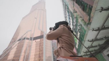 Güzel kadın şehir kış manzarasını alıyor. Başla. Şık bir kadın profesyonel kamerayla şehir manzarası çekiyor. Kadın fotoğrafçı, kar altında modern kentsel binalar alıyor.