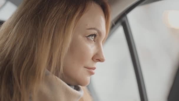 Hermosa mujer mira por la ventana desde el coche. Acción. Mujer con estilo mira por la ventana de la conducción de taxi. Mujer disfruta de la vista durante el viaje en coche — Vídeo de stock