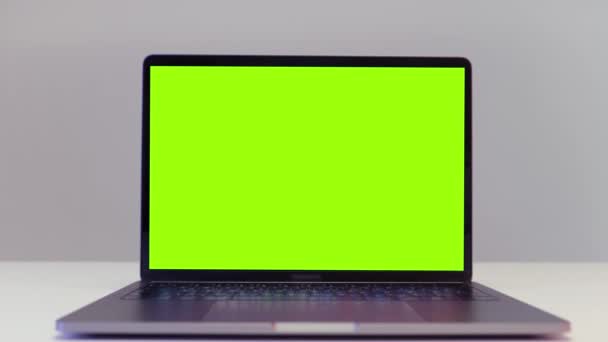 Nahaufnahme eines modernen Laptops mit grünem Bildschirm mit Chroma-Schlüssel, der auf einem Schreibtisch auf weißem Wandhintergrund steht. Handeln. Konzept der Fernarbeit und Technologie. — Stockvideo