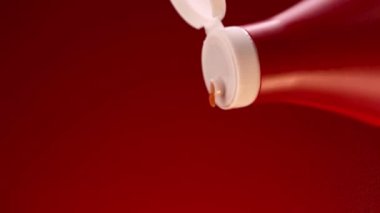 Plastik bir şişe kırmızı renkten domates sosu ekliyorum. Stok görüntüleri. Koyu kırmızı arka plana doğal ketçap dökülüyor.. 