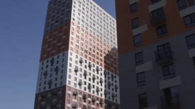 Camdan pencereleri ve küçük balkonları olan yüksek katlı yeni apartman binalarının ön cephesi. Başla. Uygun fiyatlı konut kavramı.