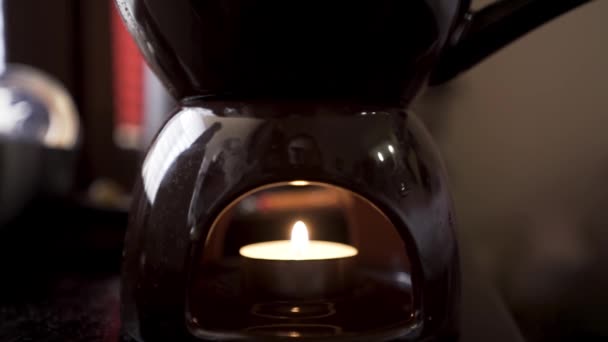 Primer plano de una pequeña vela encendida dentro de un candelabro con aceite aromático. Acción. Concepto de meditación y relajación en un ambiente tranquilo y oscuro. — Vídeos de Stock