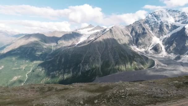 Vista desde la cima de la colina de la cordillera nevada sin fin. Clip. Impresionante naturaleza salvaje con nubes flotando sobre enormes montañas. — Vídeos de Stock