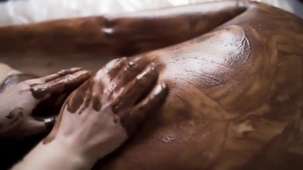 Soins spa au salon de beauté bien-être. L'action. Gros plan du massage du dos avec café hydratant et masque au chocolat. — Video