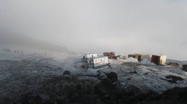 Karavan ve makinelerle dolu bir jeolojik üssün tepesinden görüntü. Şarjör. Dağlardaki sisli hava karla kaplı, bilim konsepti.