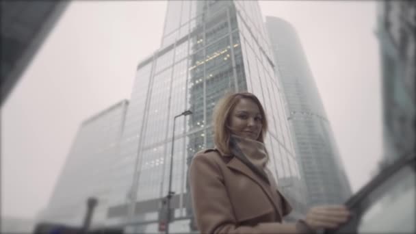 Business lady getting out of a car in the city street with high rise buildings. Action. Bottom view of a beautiful caucasian middle aged woman in brown coat leaving a car or a taxi on the background — Stock Video
