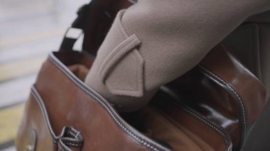 İki altın metal perçinli kadın deri çuvalı. Başla. Kadın elinin, güzel, kahverengi, gerçek bir deri çantayı açıp içinde bir şey aramasına yakın durun..