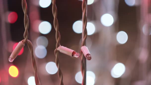 LED vánoční věnce blikající na pozadí rozmazaných bokeh světel. Koncept. Zblízka blikající světla světle růžové barvy, Nový rok a vánoční čas. — Stock video