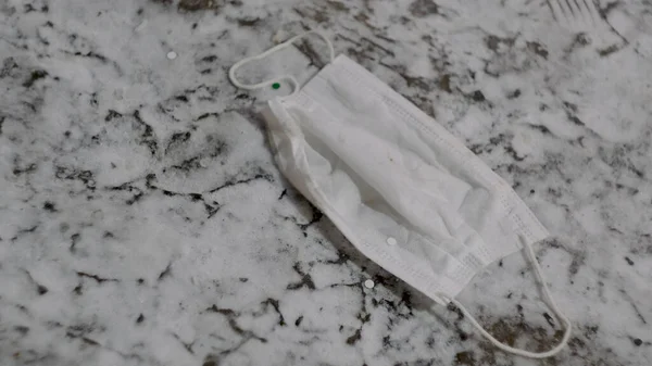 Medical mask being stepped on. Concept. Close-up of medical mask lying on marble floor. Medical mask is thrown to floor and trampled underfoot — Stock Photo, Image