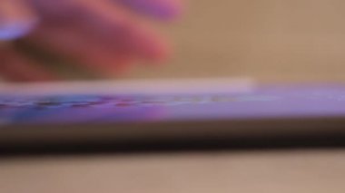 Masada tablet kullanan bir adamın yakın çekimi. Kavram. Bulanık arkaplanda yeni tablet kullanılıyor. Uygulamaları açmak için dokunmatik tablete tıklayın