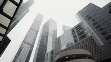 Aşağıdan görünen modern cam gökdelenler. Başla. Şehir merkezinde sisli bir havada güzel bir iş bölgesi..