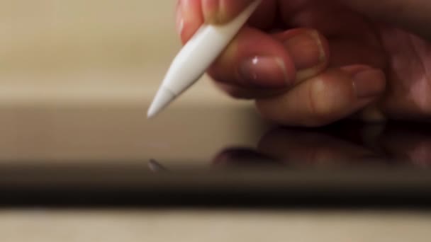 Close up of female freelancer or graphic designer working on a digital tablet using stylus pen. Concept. Woman hand writing on a graphic tablet, side view. 