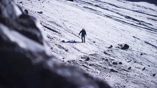 A man walking on snowy mountain slope on a winter sunny day. Clip. Hiker trekking in mountains, concept of active lifestyle. — Fotografia de Stock