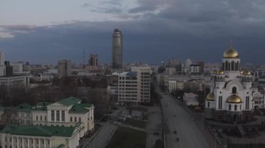 Azizler, Rusya ve Ekaterinburg adına Kan Kilisesi. Stok görüntüleri. Altından kubbeleri ve arka planında Vysotsky gökdeleni olan güzel bir kilisenin akşam manzarası.