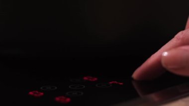 Kadın parmağının elektrikli yemek panelini kapatması ve ışığı açması. Kavram. Evde, mutfakta yemek pişirmenin sonu.. 