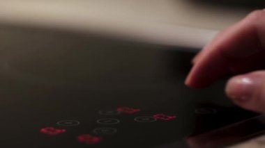 Modern bir indüksiyon soba kontrol paneli, ev aletleri. Kavram. Kadın elinin dokunduğu sensör paneli, mutfak için modern teknolojiler.. 