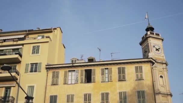 Botten utsikt över ett gammalt klocktorn och ett gult bostadshus på dimmig himmel bakgrund. Börja. Begreppet arkitektur i en gammal europeisk stad. — Stockvideo